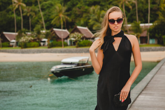 游艇奢华性感迷人的女人穿着黑色礼服在豪华度假酒店的码头上摆造型 戴着墨镜 暑假 热带海滩人户外船