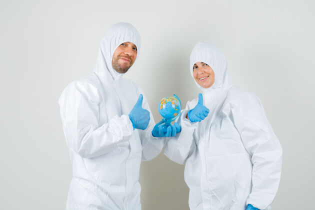 医疗两个医生拿着世界地球仪 穿着防护服竖起大拇指年轻实验室站