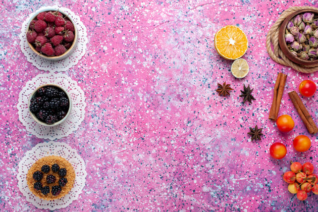 覆盆子小黑莓蛋糕的顶视图 浅粉色表面上有覆盆子和新鲜黑莓滴滴浆果