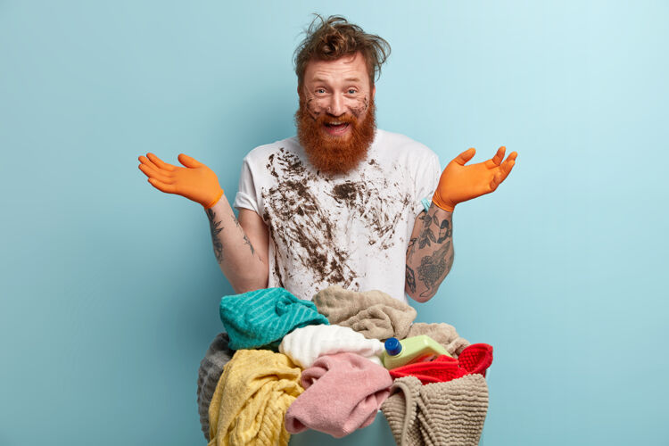 乐观的快乐的红发男人 浓密的鬃毛 摊开双手 在家洗完衣服后玩得很开心横向的手套满意的