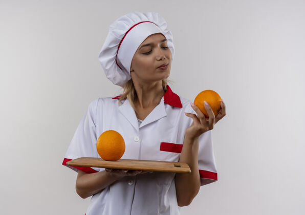 女想着年轻的女厨师穿着厨师制服 手里拿着砧板 看起来是橙色的制服手思考