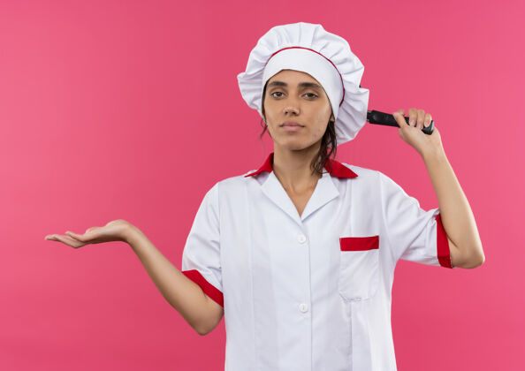 手未出狱的年轻女厨师身穿厨师制服 手持煎锅 用手指着旁边有复印空间的地方厨师边点