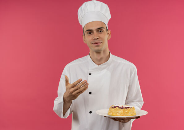 盘子高兴的年轻男厨师穿着厨师制服 拿着蛋糕放在盘子上 留有复印空间拿着制服蛋糕