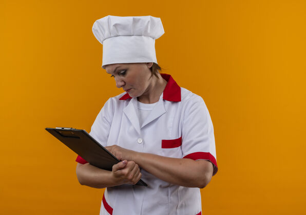 中年想着中年女厨师穿着厨师制服看着她手里的剪贴板和复印空间剪贴板厨师制服