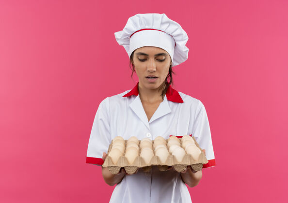 穿穿着厨师制服的年轻女厨师手拿着一批鸡蛋 看着有复印空间的鸡蛋厨师批制服