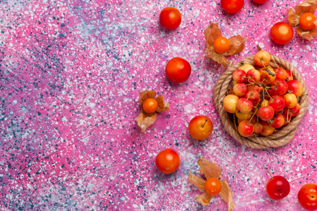 浆果在浅粉色的桌子上俯瞰新鲜的甜樱桃和李子李子灌木粉红色