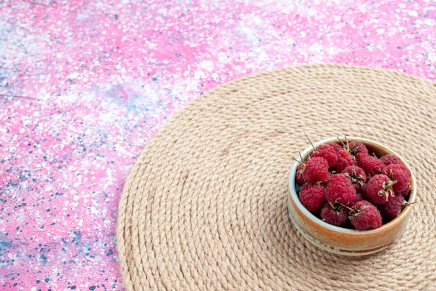 浆果正面图新鲜的红色覆盆子在粉红色背景上的小罐子里美味食物健康