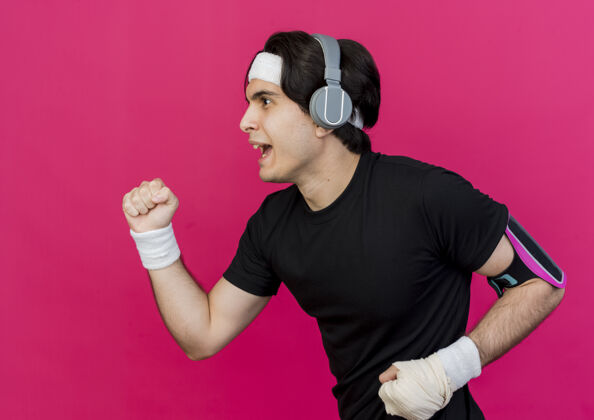 智能手机年轻的运动型男子穿着运动服和头带与手机和智能手机臂带努力工作粉色工作型头带