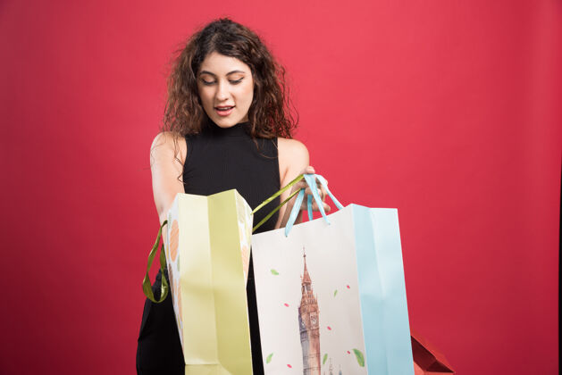 购买在红色背景上展示她的购物的女人高质量的照片购买脸携带