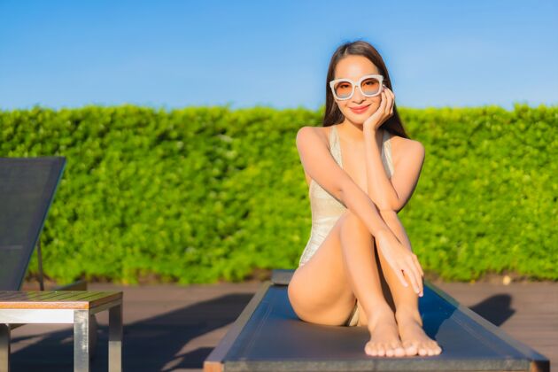 苗条美丽的亚洲年轻女子在度假酒店的室外游泳池周围放松的肖像阳光游泳热带