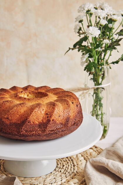 棕色美丽的镜头美味的环蛋糕放在一个白色的盘子和一个白色的花靠近它美味新鲜菜肴
