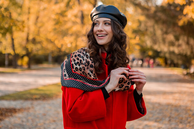 穿着迷人时尚微笑的女人卷发漫步在公园穿着暖红色外套秋季时尚 街头风格 戴贝雷帽和豹纹围巾女孩苗条服装