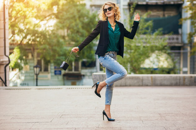 鞋子普里蒂时尚的女人穿着蓝色牛仔裤走在街上 穿着夹克和绿色上衣 时尚配饰 优雅的风格 时尚潮流的春天街道穿配件