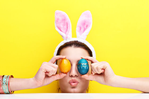 空戴着兔子耳朵吃复活节彩蛋的快乐的年轻女人女孩节日象征