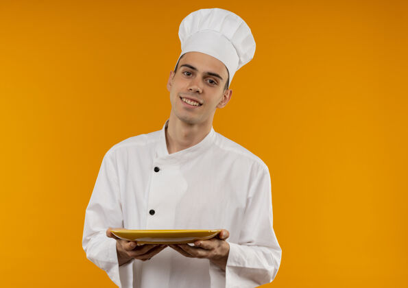 男笑容可掬的男青年帅气地穿着厨师制服拿着盘子与复印空间酷戴着盘子