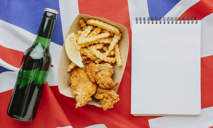 英国盘子上的鱼和薯条的俯视图 带笔记本和啤酒瓶薯条油炸鱼
