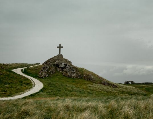 草地放在石山上的基座上的十字架的镜头山符号草
