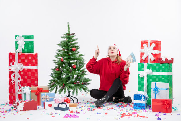 礼物前视图年轻女子围坐在白墙上拿着飞机票的礼物举行圣诞树周围