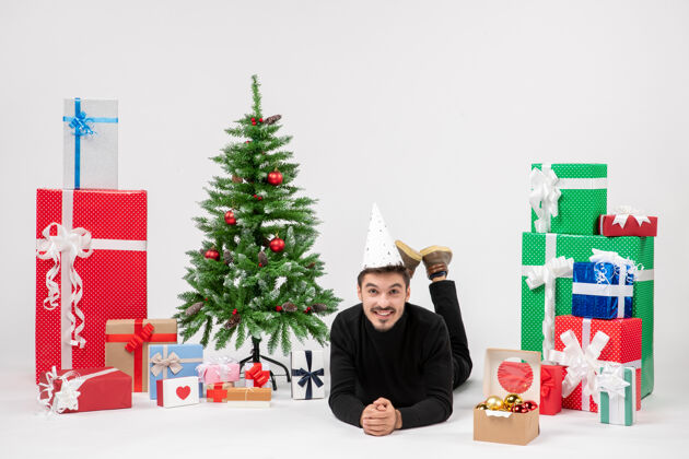 模型正面图：年轻人正快乐地躺在白色墙上的节日礼物周围礼物前面墙板