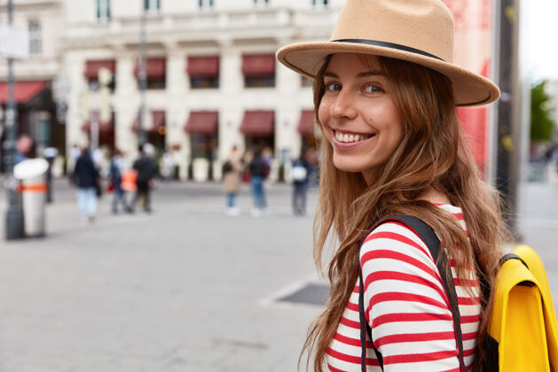 时尚在街上漫步的快乐女性游客的水平视图条纹背包城镇
