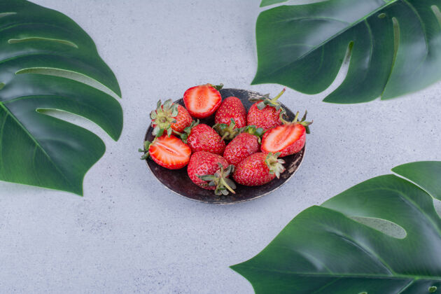 可口一小捆草莓和装饰性的叶子放在大理石背景上叶子水果草莓
