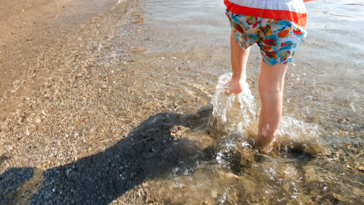 婴儿特写镜头 孩子的脚在沙滩上的海水中奔跑台阶成长热