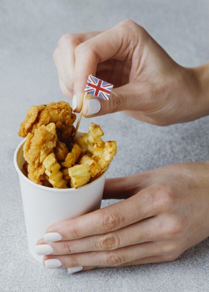 英国把英国国旗插在纸杯里的炸鱼薯条盘子里的女人菜国旗薯条