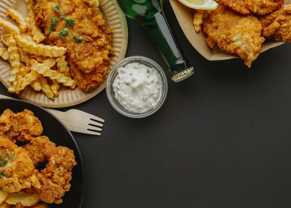美食盘子里的鱼和薯条的顶视图 还有餐具和啤酒瓶复制空间餐美食