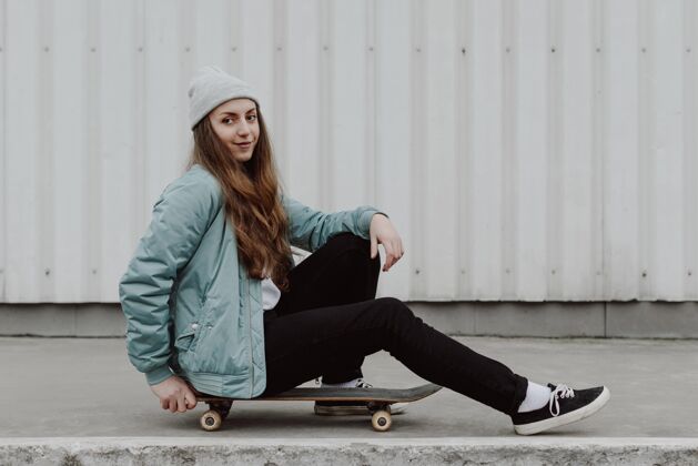 滑板坐在户外滑板旁边的女滑板手城市滑板女人