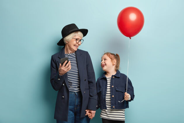 笑着童年 家庭 关系观念时尚奶奶是现代科技的先进使用者 牵着小孙女的手孙女年长小眼镜