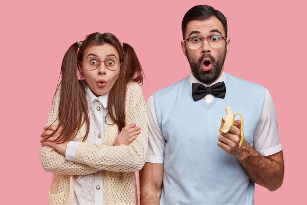 书呆子照片中惊讶的男女怪人难以置信地瞪着眼睛 吃着美味的香蕉 穿着旧时髦的衣服尴尬香蕉惊讶