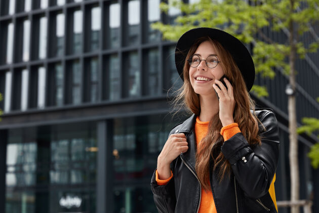 手机高兴的欧洲女人户外镜头享受智能手机上的交流 走在大都市里 面带笑容望向远方快乐科技照片