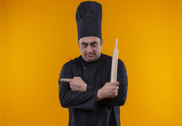厨师自信的中年男厨师身着厨师制服 手持擀面杖 手指指向黄色墙壁的一侧 留有复印空间抱男自信
