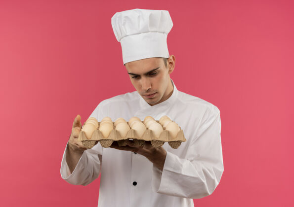 男想着年轻的男厨师穿着厨师制服看着手里的一批鸡蛋穿厨师制服