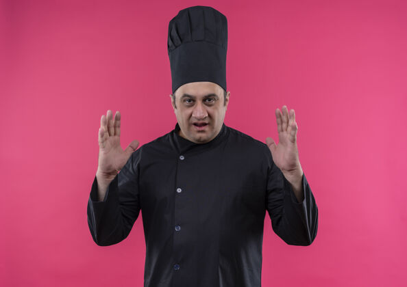 中年身着厨师制服的中年男厨师在孤立的粉红色墙上展示身材展示男厨师