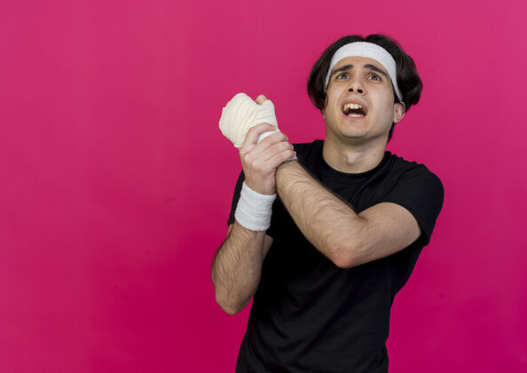 站立一个穿着运动服 戴着头巾的年轻人 正痛苦地抚摸着缠着绷带的手腕戴疼痛粉色