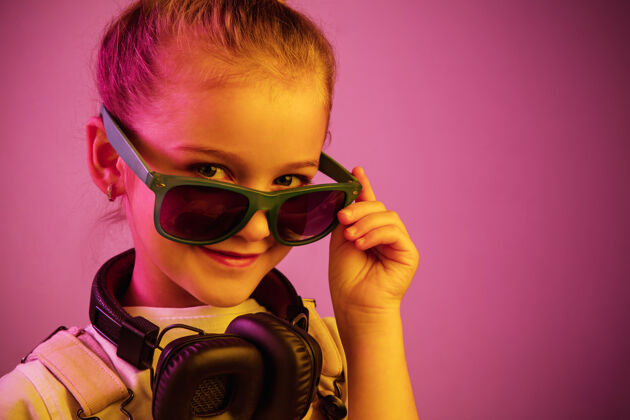 耳机戴着耳机欣赏音乐的年轻女孩的霓虹灯肖像可爱迪斯科太阳镜