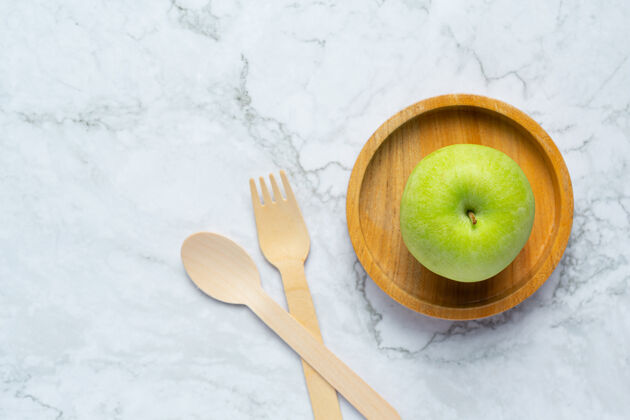 健康把青苹果放在木碗里 旁边放一个木勺和叉子纤维青苹果果味