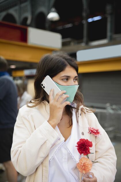 冠状病毒戴着口罩的女人一边拿着花一边打电话感染爆发女人