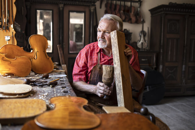 木制高级木匠在他的老式木匠工作室里检查木材的音质手持木工硬木