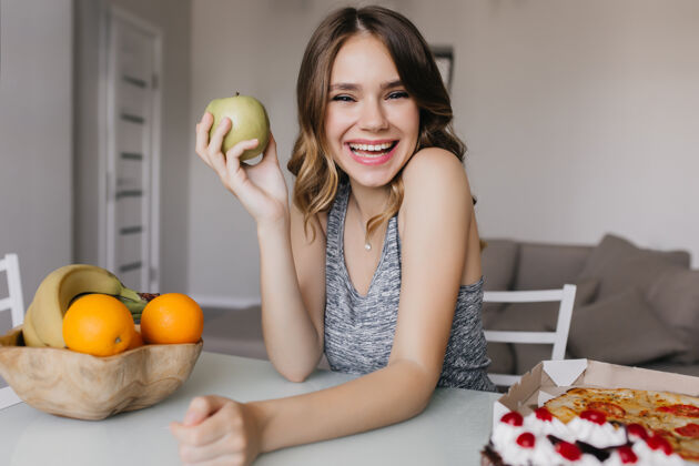 微笑兴奋的欧洲女孩在饮食中享受美味的水果美丽的女模特拿着苹果微笑着水果美味美丽