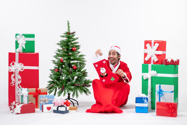 圣诞老人圣诞老人微笑着坐在地上 穿着圣诞袜 在白色背景上装饰圣诞树地面穿袜子