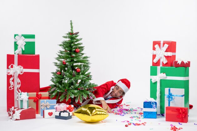 礼物圣诞气氛与圣诞老人躺在圣诞树旁的礼物在不同颜色的白色背景下圣诞老人说谎礼物