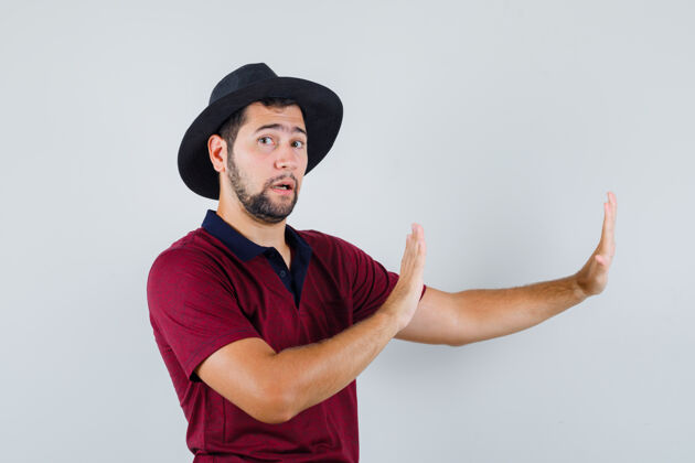 随意年轻的男性举手为自己辩护 穿着t恤 戴着帽子 看上去很麻烦正面图男人提高肖像