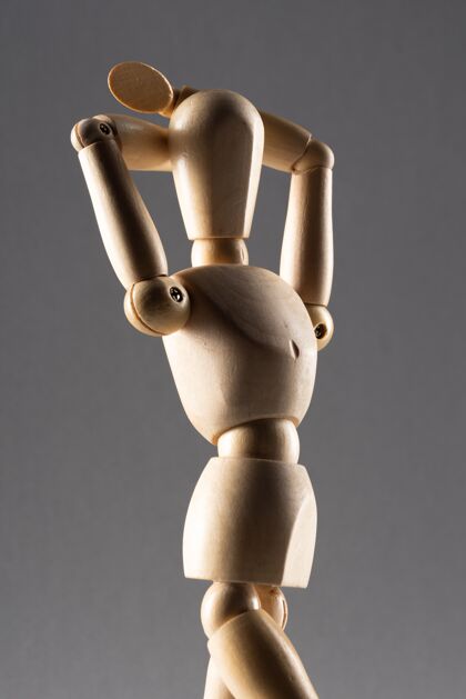 手垂直特写一个木制姿势玩偶与双手背后的头部在阴影中姿势垂直头