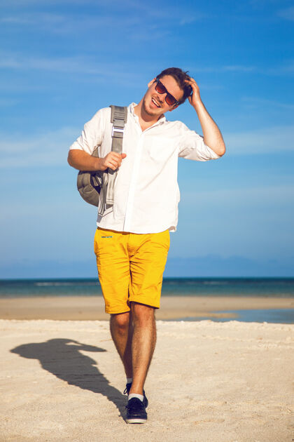 男孩时尚户外写真帅哥穿着鲜艳的时尚休闲装漫步在热带海滩天空享受户外