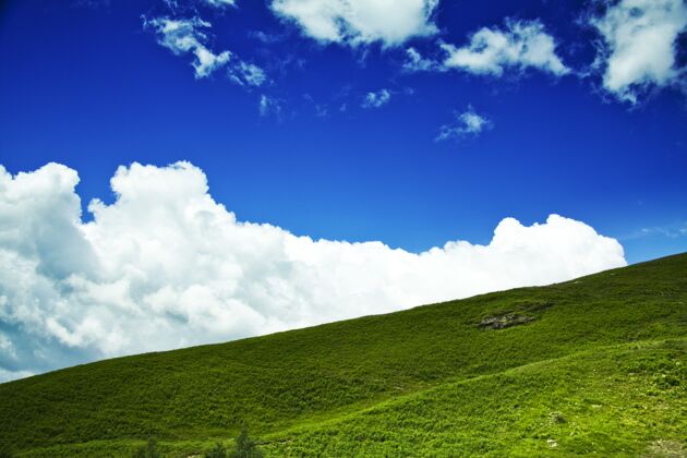 户外低角度拍摄了一座绿色的小山 背景是多云的蓝天草自然山
