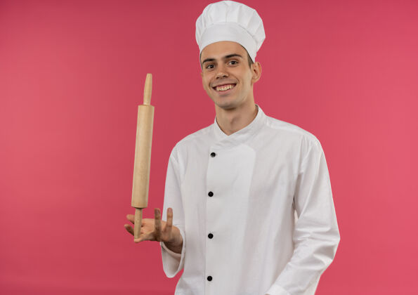 男微笑的年轻男厨师穿着厨师制服 手指上拿着擀面杖厨师滚着拿着