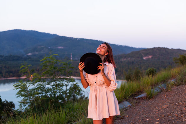 漂亮穿着夏装的年轻白种女人的浪漫写真 在山上的公园里享受着令人惊叹的热带海景耳环配饰自然