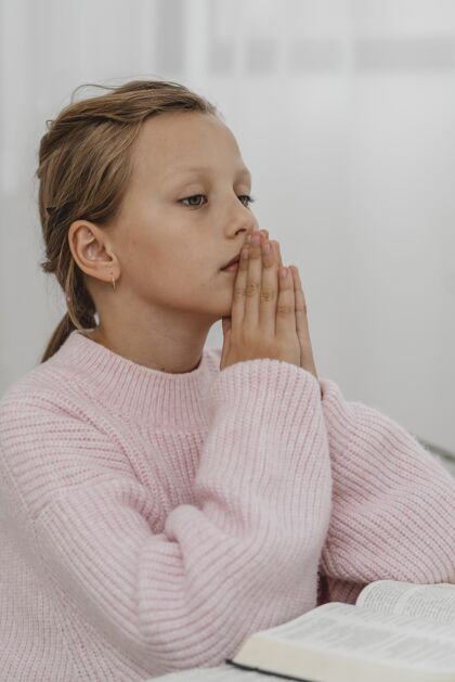 祈祷女孩用圣经祈祷的侧视图圣经信仰虔诚